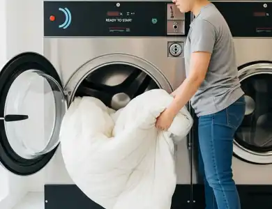 A Person Easily Loading A Large, Fluffy King Sized Comforter Into The Door Of A Spacious, Modern Commercial Washing Machine.